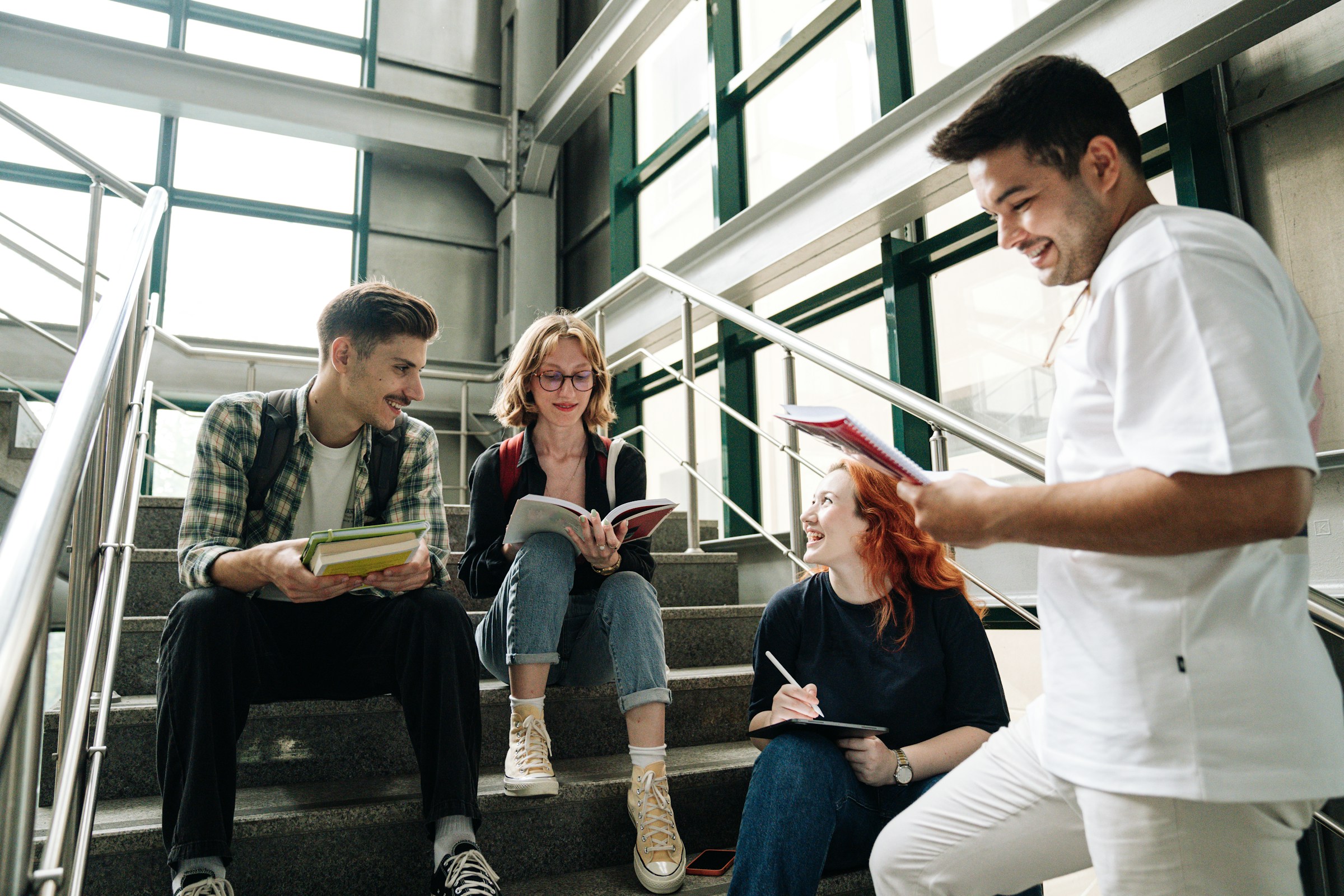 A group of college students sit on stairs in collaboration