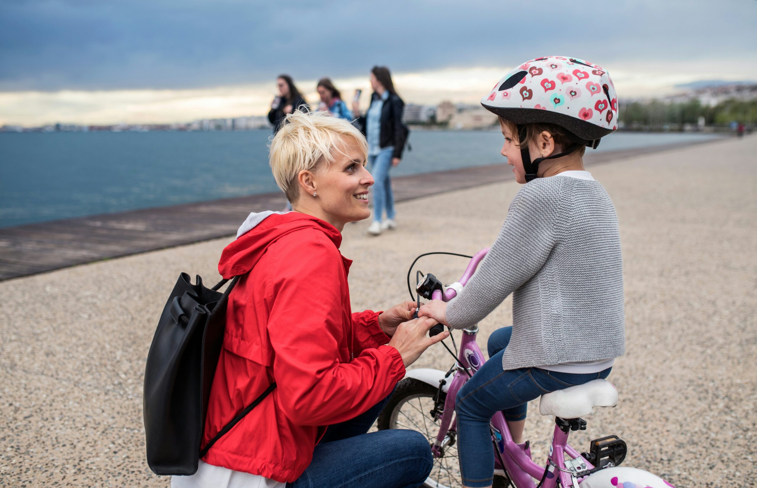 A mother with her child sitting on a bike near the shoreline