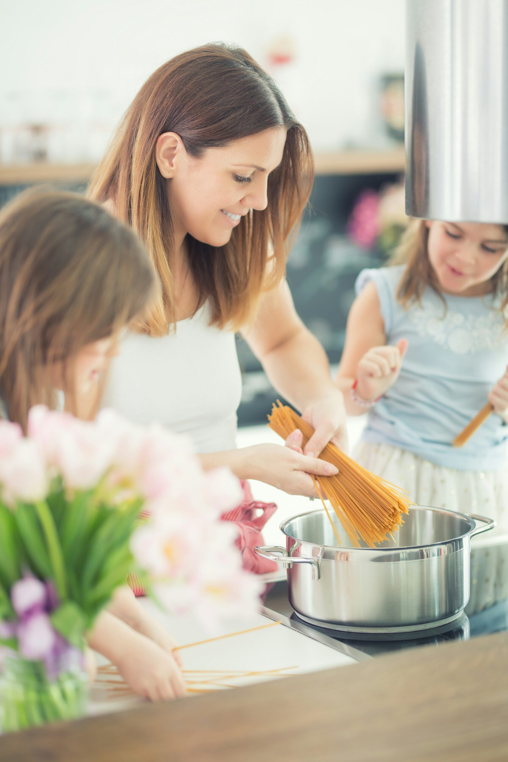 A mother cooking pasta with two children