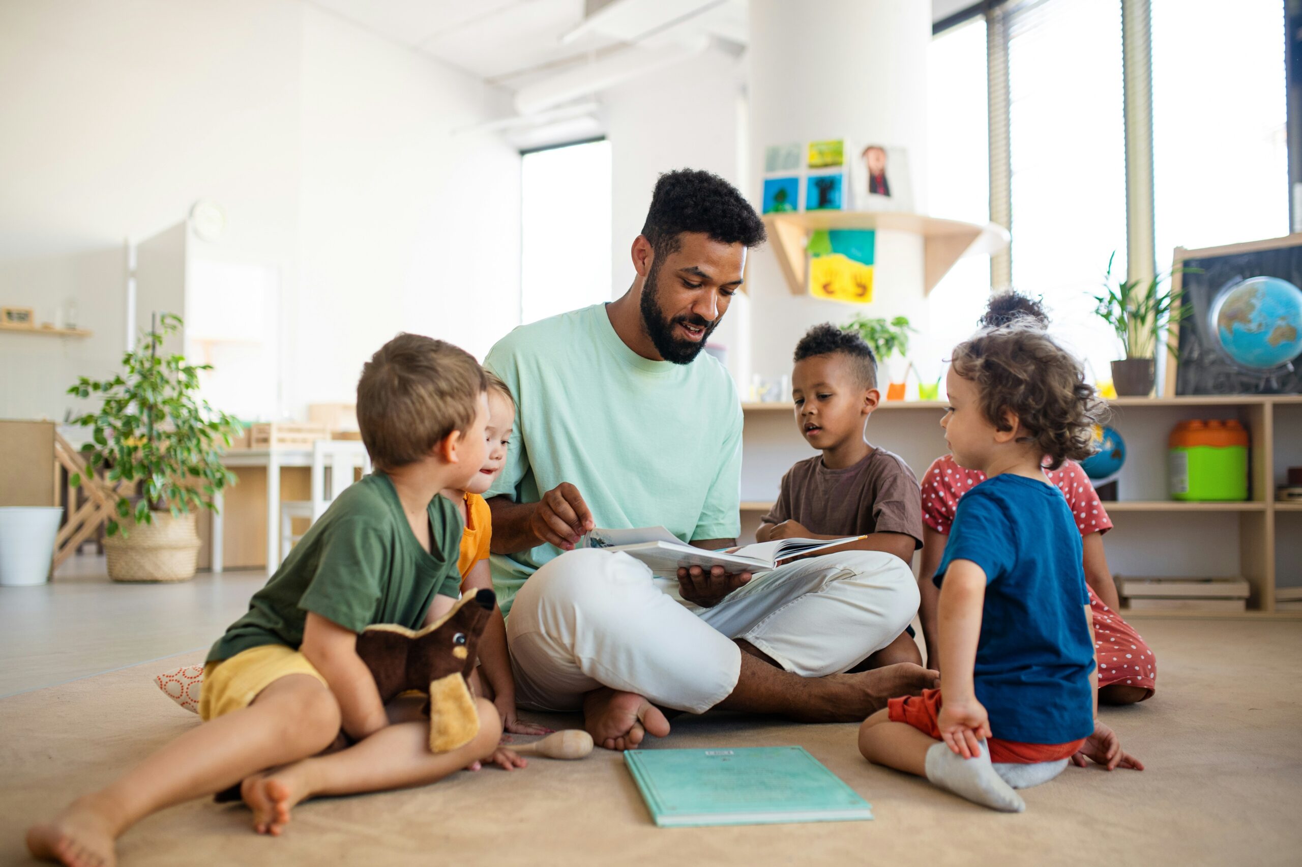 A teacher sitting on the floor with several young students