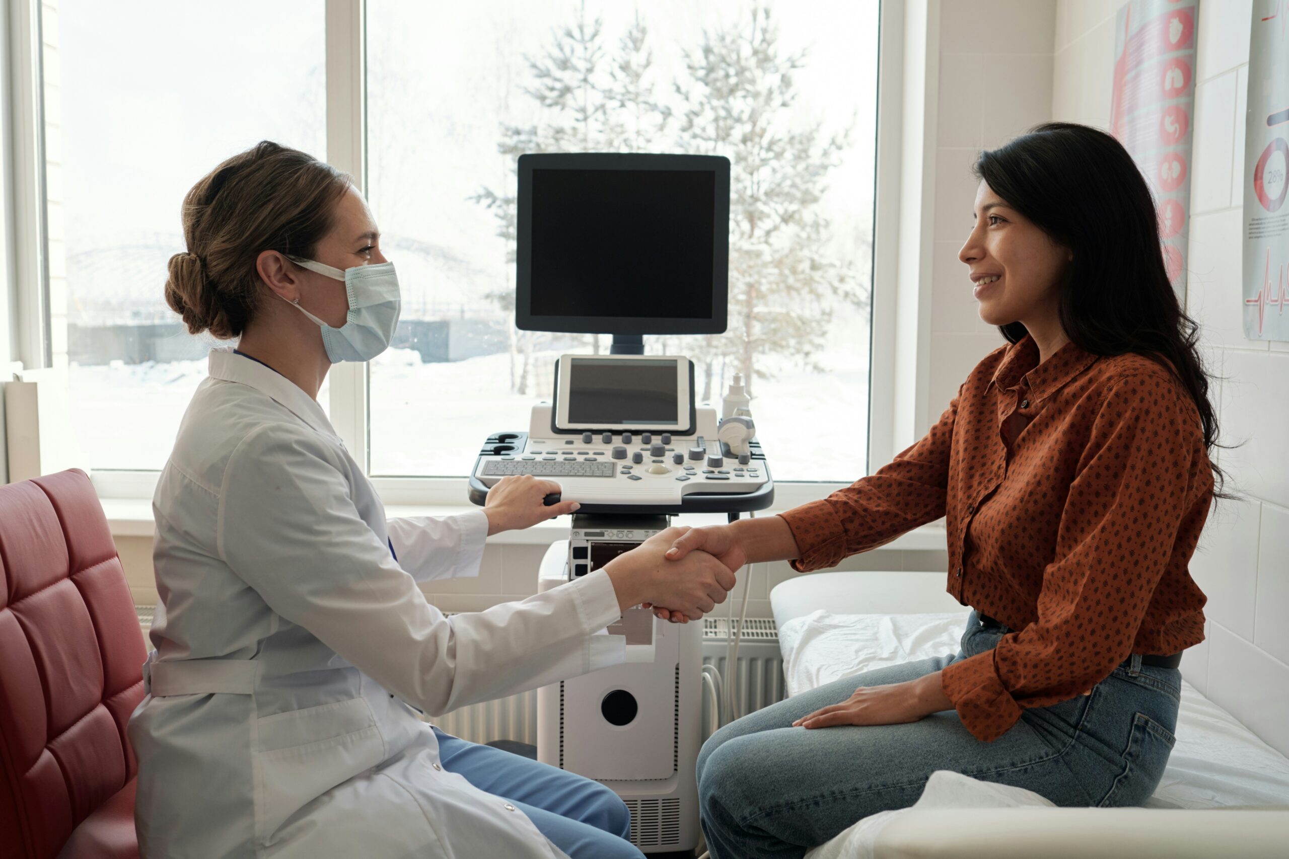getty-images-yZzOlLpiQPE-unsplash A smiling patient shakes hands with her doctor in an examination room