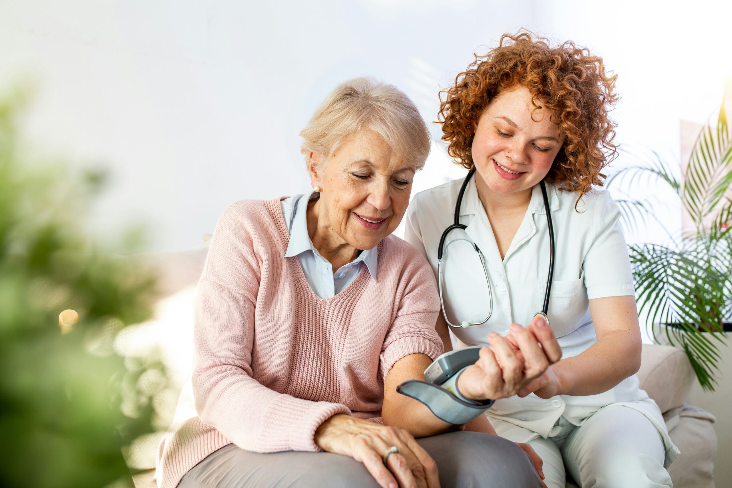 getty-images-QbrSfEg3gW4-unsplash A health care professional smiles as she takes the blood pressure of an older patient