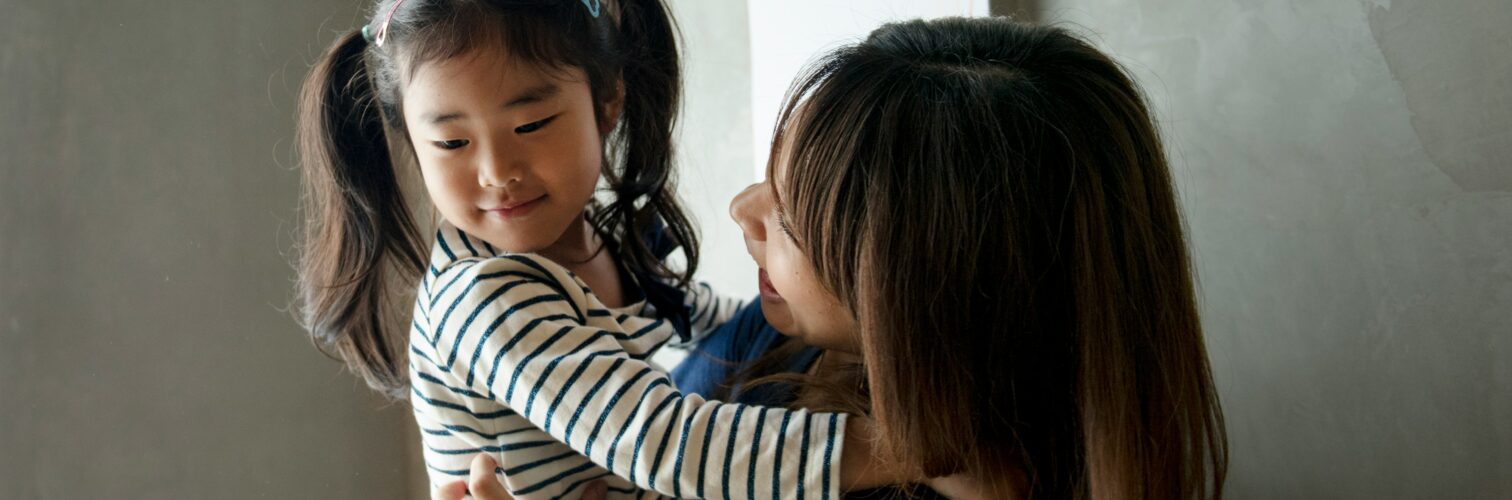A mother holds her smiling daughter in pig tails