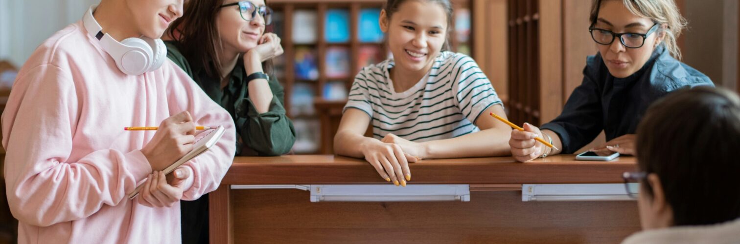 Students gather around a laptop in a library