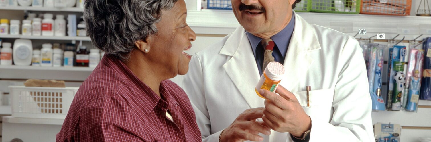 A pharmacist discusses a prescription with an elderly patient