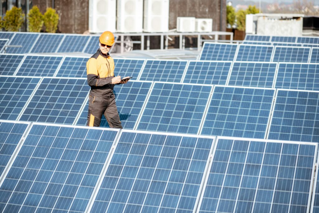 An engineer walks through a field of solar panels and records information